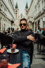 Handsome man with fashionable glasses sitting in modern coffee shop outdoor