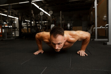 Fototapeta na wymiar Sport close-up shot of STRONG Sexy Young fashion sport man, fitness muscle model guy making push ups exercise over dark background