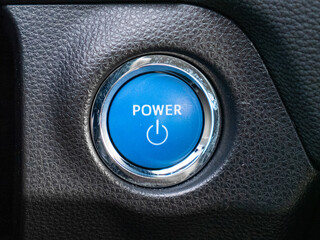 Power button on the control panel inside a blue illuminated hybrid vehicle