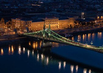 Beautiful midnight scene in the lovely Budapest with the green Petőfi Bridge, trams and Corvinus University building