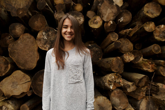 Cheerful young good looking smiling woman with clean taned skin and black straight hair posing outdoors on wooden background smiling, laughing at good joke, wearing stylish clothes