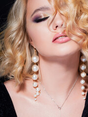 Gorgeous blonde, portrait on a black background. Beautiful young girl, makeup for the celebration.