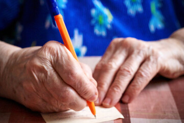 elderly woman writes on blank paper