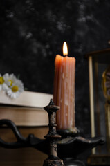 vintage candle on the table with a stack of books and daisies