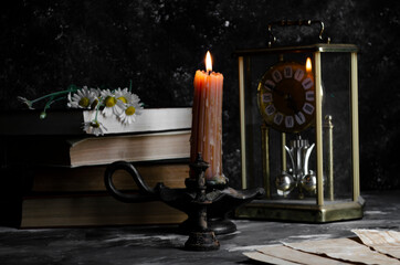 vintage candle on the table with a stack of books and daisies