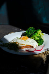 fresh broccoli with fried eggs on a wooden board