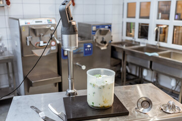 Mixed milkshake and professional blender on the table at the kitchen, making a base for ice cream...