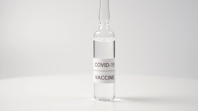 Glass ampoule with a coronavirus vaccine on a white surface. Experimental dose for bacteriological research and testing. Vaccination from COVID-19
