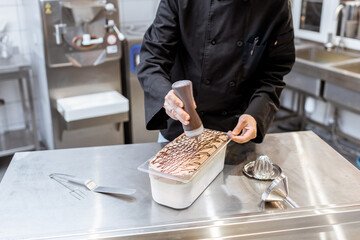 Confectioner pouring chocolate on the ice cream, making ice cream on the kitchen of a small manufacturing or restaurant