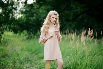 Beautiful carefree woman in dress in green fields being happy outdoors and enjoying spending time with nature. Spring and summertime.