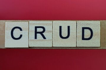 text the word crud from gray wooden small letters with black font on an red table
