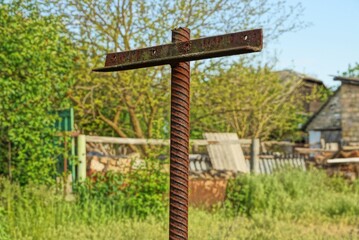 one brown long pin of rusty reinforcement on the street against a background of green vegetation