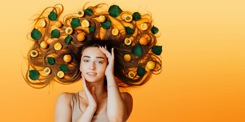 summer girl lying on background with apricots on long hair, concept female natural beauty care, head of young woman high angle view