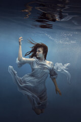 Fototapeta na wymiar Portrait of a girl in a blue dress under water 