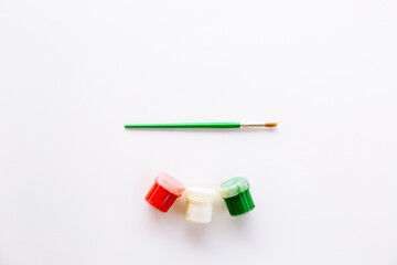 Three different colors white, red, green and brush for painting. Tools for painting or decorating in the New Year's palette. Jars with acrylic or gouache.