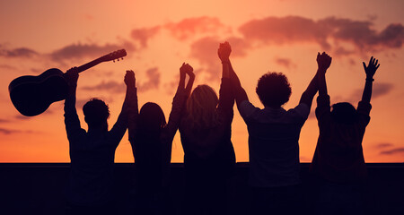 Fototapeta premium Unrecognizable friends with raised arms during sunset