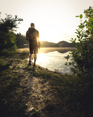 man stands on lake shore during sunrise
