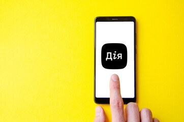 A male hand holds a smartphone, points a finger, types. Communication on a smartphone, correspondence. Place for text. Smartphone in hand on a yellow  background.