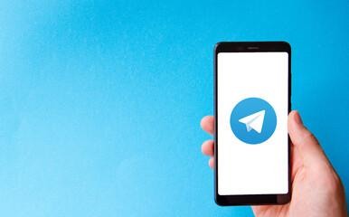A male hand holds a smartphone, points a finger, types. Communication on a smartphone, correspondence. Place for text. Smartphone in hand on a blue  background.