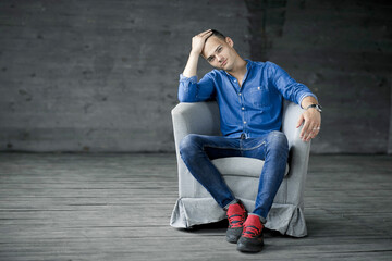 Sad man sitting in in a chair dark room. Depression and anxiety disorder concept. Depressed man sitting against a wall and looking down in studio near the big window.