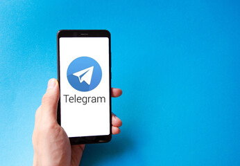 A male hand holds a smartphone, points a finger, types. Communication on a smartphone, correspondence. Place for text. Smartphone in hand on a blue  background.
