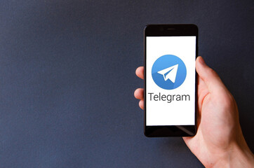 A male hand holds a smartphone, points a finger, types. Communication on a smartphone, correspondence. Place for text. Smartphone in hand on a gray  background.