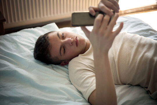 young boy in bed with a smartphone