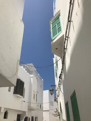 Fototapeta na wymiar Asilah, Morocco-August 04 2019: Narrow old street in the medina of Asilah with tourists