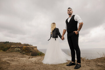 Couple In Love holding hands while looking at different sides and enjoying the nature and beautiful landscaped. The strength of love. Romantic couple having beautiful moments of happiness and joy