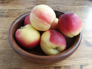 Fresh nectarines in a wooden brown bowl