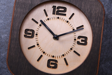 Wooden clock made in hand on wooden background. Close-up. Place for text.