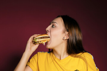 fUNNY COMIC PHOTO OF EATING BURGER GIRL WITH GREAT WISH on pink background. Big true love to burger and fastsood. McDonald's CONCEPT.