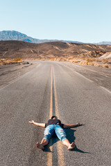 Obraz premium A woman lying barefooted on an empty road in the Death Valley