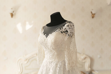 Fototapeta na wymiar Gorgeous wedding dress on a mannequin in a white room.