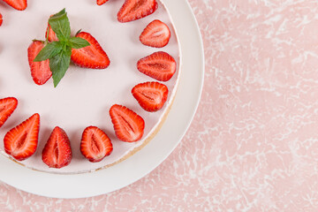 Sweet breakfast, delicious cheesecake with fresh strawberries and mint, homemade recipe without baking, on a pink stone table. Copy space.