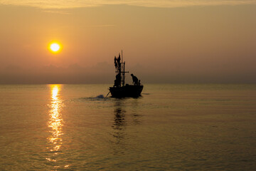Fototapeta premium Silhouette of two people on a fishing boat that is about to go fishing in the morning sun.copy space.