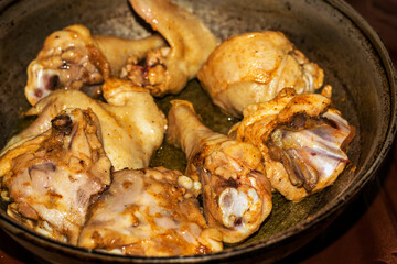 Chicken pieces are fried until golden in a pan with oil. Harmful fatty food, fast food.
