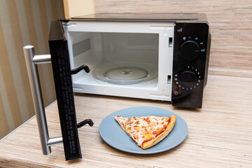Plate with slice of pizza next to the microwave