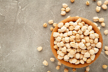 Fototapeta na wymiar Uncooked dried chickpeas in wooden bowl on grey background. Vegan food concept