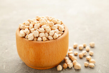 Uncooked dried chickpeas in wooden bowl on grey background. Vegan food concept