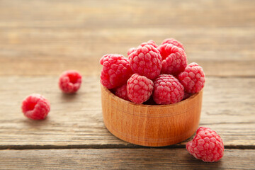 Ripe raspberries in wooden bowl on grey background. Top view