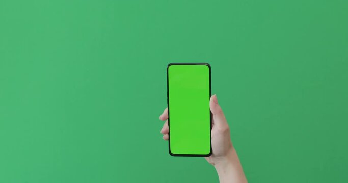 Young female hand show smartphone with green screen on green background