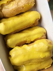 Delicious eclairs with yellow glaze in a box