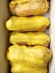 Delicious eclairs with yellow glaze in a box
