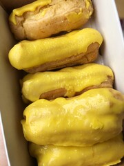 Delicious eclairs with yellow glaze in a box