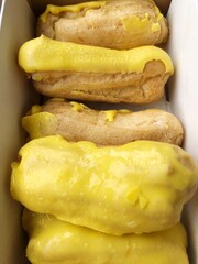 Delicious eclairs with yellow glaze in a box