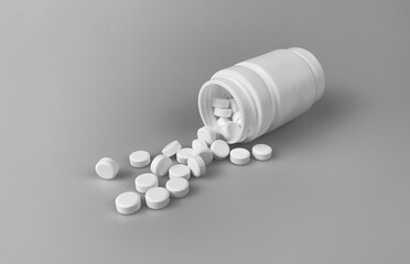 White pills spilling out of a drug bottle.Pills on white  table.