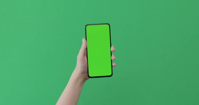 Young female hand touch smartphone with green screen on green background