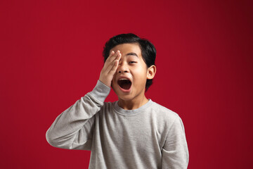 Young Asian boy closed one of his eye with surprised expression, shocked amazed terrified gesture
