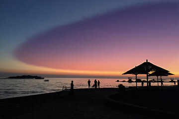 Fantastic colors of the sky on the beach at sunset and silhouettes of people on the shore